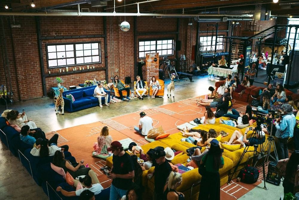 An overhead view of a sunlit brick loft full of guests on couches and yellow cushions at Biohacking Safari